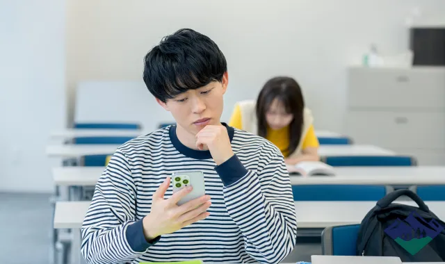 スマホを見て微妙そうな表情を浮かべる男子大学生