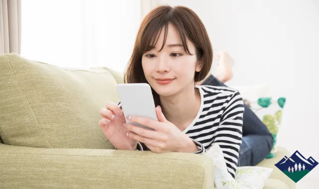 ソファに横になってスマホを操作する女性