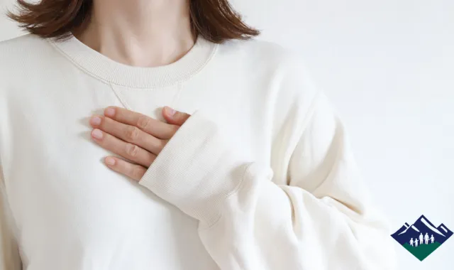 自分の胸に手を当てる女性