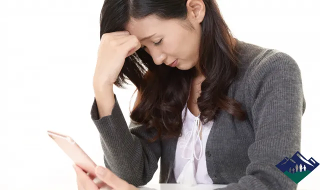 スマホを片手に落ち込む女性