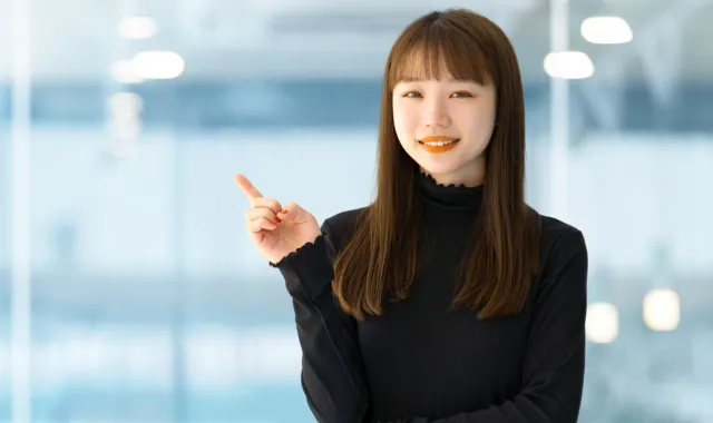 人差し指を立てて提案する長髪の女性